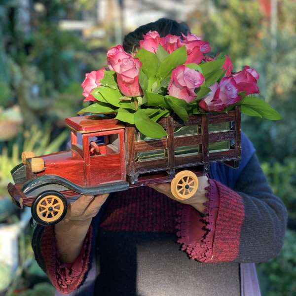 Pink roses arranged in a wooden truck-shaped container
