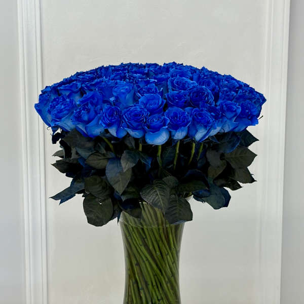 Large bouquet of vivid blue roses in a clear glass vase