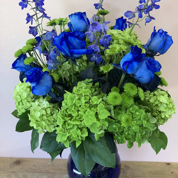 Blue roses and green hydrangeas in a dark glass vase