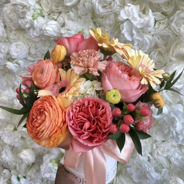 Mixed bouquet of pink, peach, and yellow flowers in a white box with a ribbon
