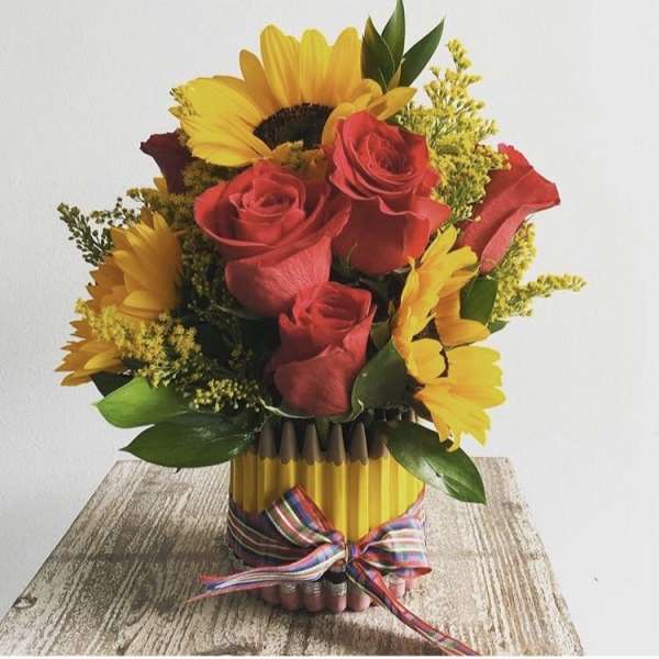 Bouquet of red roses and yellow sunflowers in a pencil vase