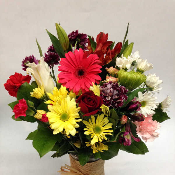 Mixed bouquet of colorful flowers in a burlap-wrapped vase