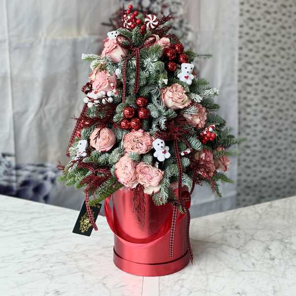Pink roses and holiday greenery arranged in a red hatbox with ribbon and teddy bear picks