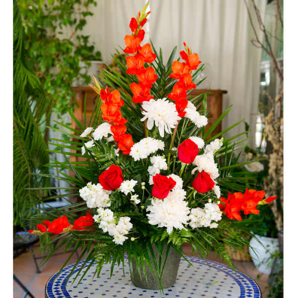 Tall floral arrangement with red and white flowers in a gray vase