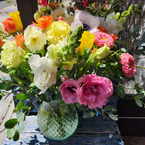 Mixed bouquet in a glass vase with pink, yellow, white, and orange flowers