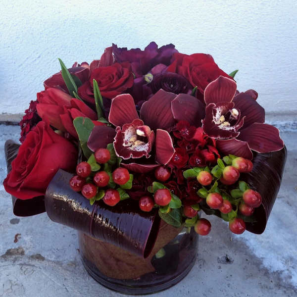 Red roses and burgundy orchids in a dark vase