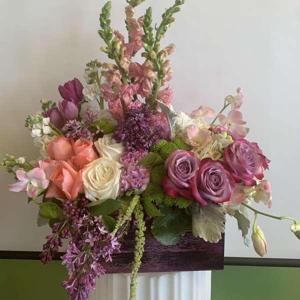 Mixed bouquet of pink, peach, and white flowers in a rectangular container