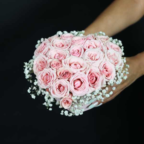 Handheld bouquet of pale pink roses with white baby's breath