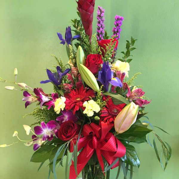 Tall mixed bouquet in a glass vase with red, purple, and yellow flowers