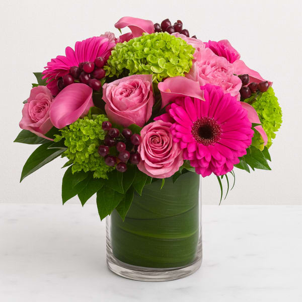 Pink roses and gerbera daisies in a glass vase with green hydrangeas