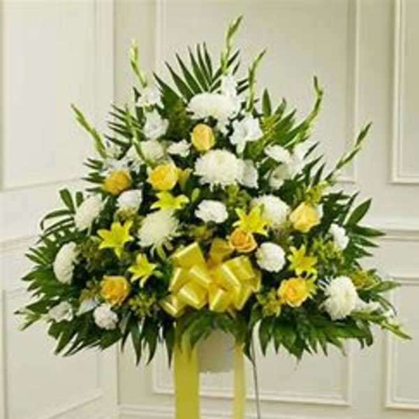 Standing floral spray with white and yellow flowers and a yellow ribbon