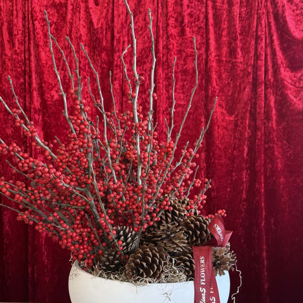 Red berry branches and pinecones in a white bowl vase