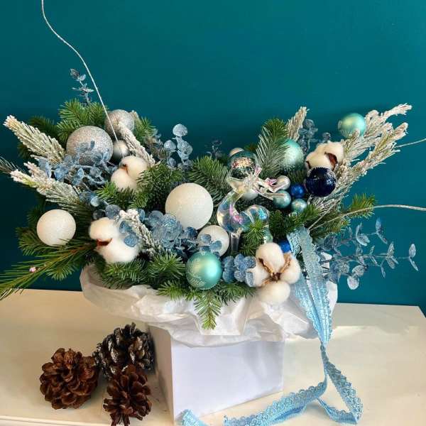 Holiday arrangement with pine, cotton bolls, and blue ornaments in a white box