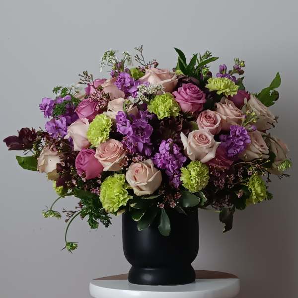 Large bouquet of pink and purple roses in a black vase