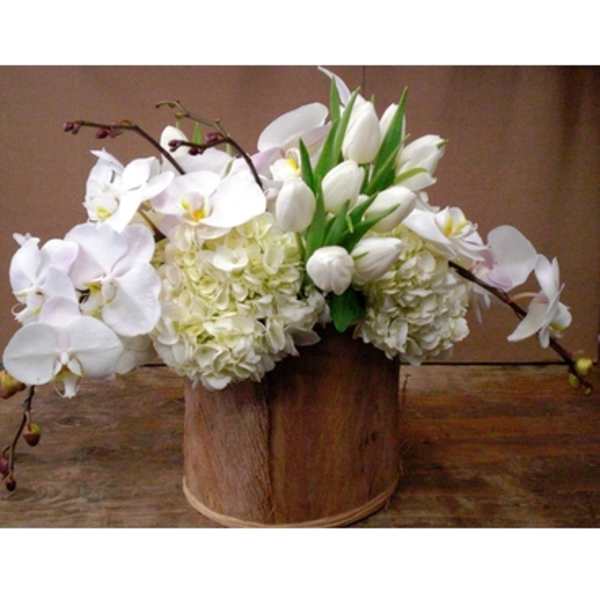 White orchids and tulips arranged in a wooden container