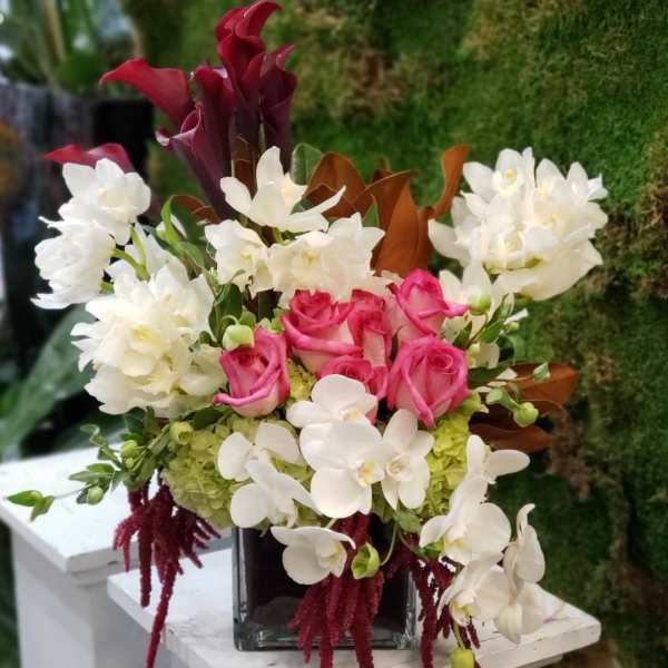Pink roses and white orchids in a square glass vase