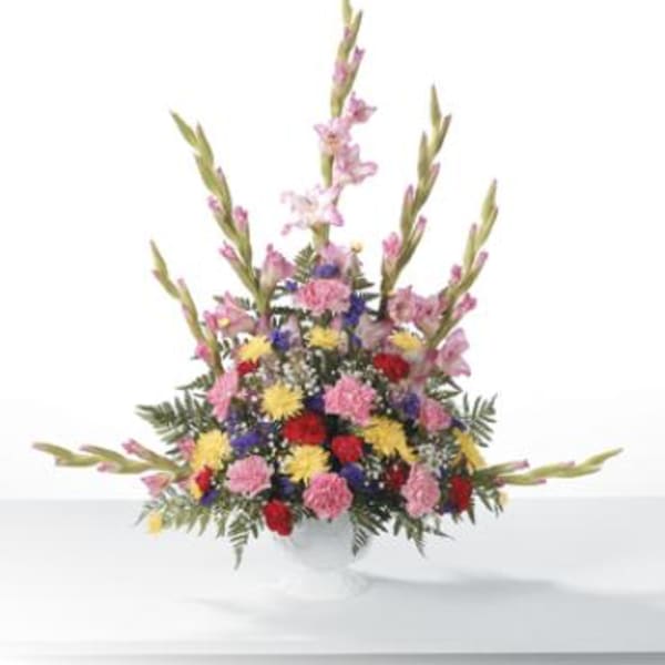 Tall mixed bouquet of pink, red, yellow, and purple flowers in a white vase