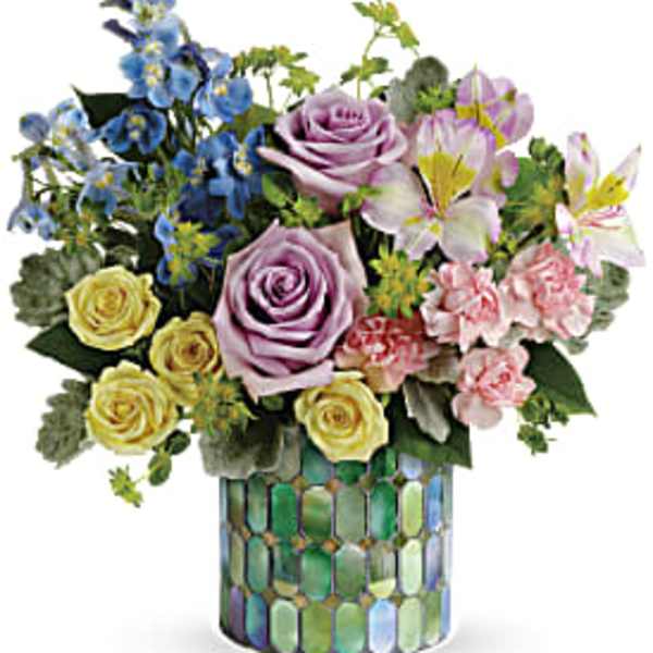 Mixed bouquet of roses, lilies, and blue flowers in a mosaic vase