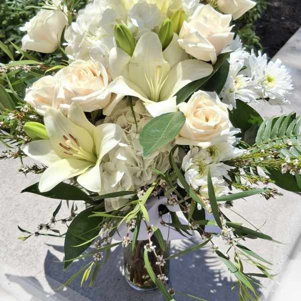 White lilies and cream roses arranged in a glass vase