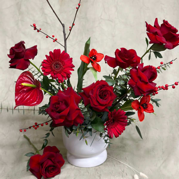 Red roses and gerbera daisies arranged in a white vase