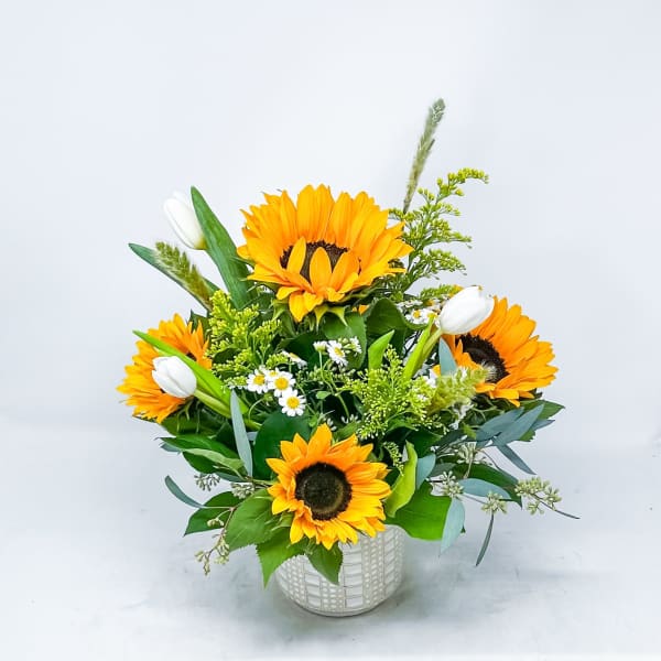 Sunflower bouquet in a white patterned vase with white tulips
