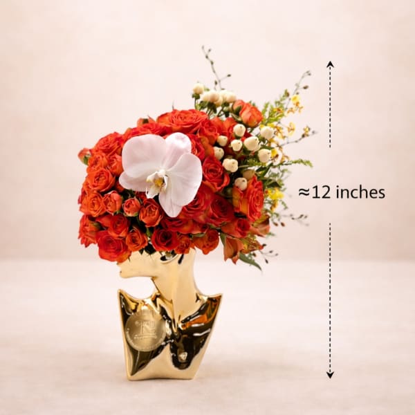 Red rose arrangement in a gold vase with a white orchid accent