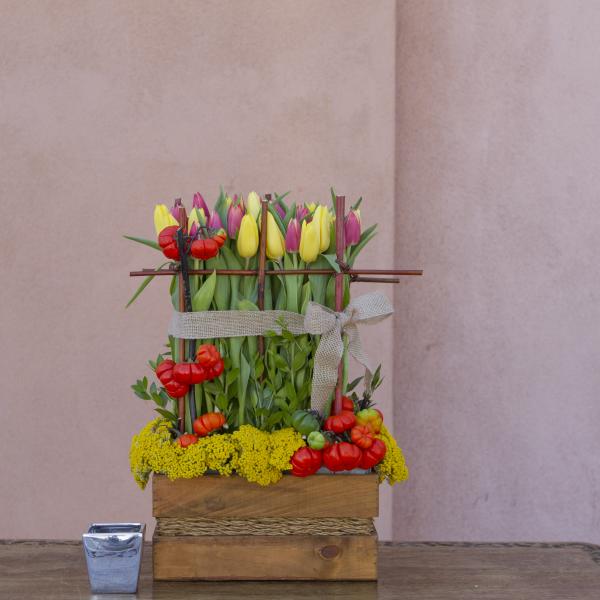 Tulips and small pumpkins arranged in a wooden box with a burlap bow