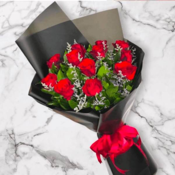 Bouquet of red roses wrapped in black paper with a red ribbon