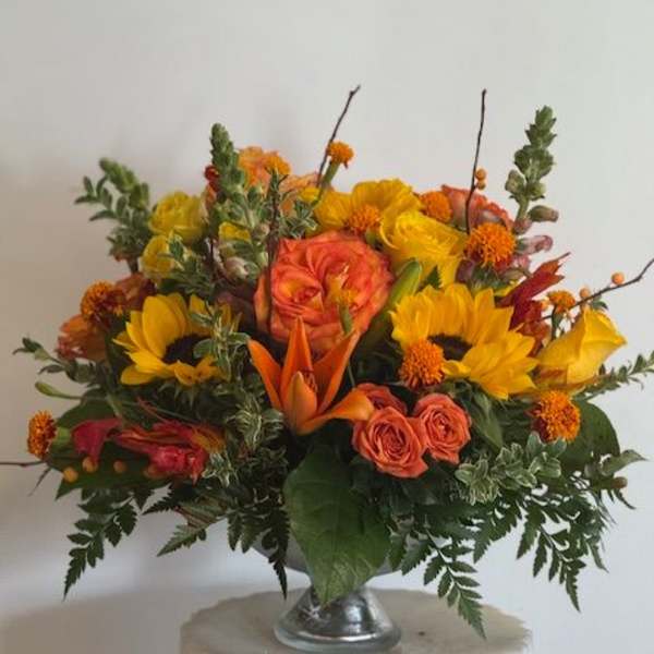 Orange and yellow mixed flower arrangement in a silver vase