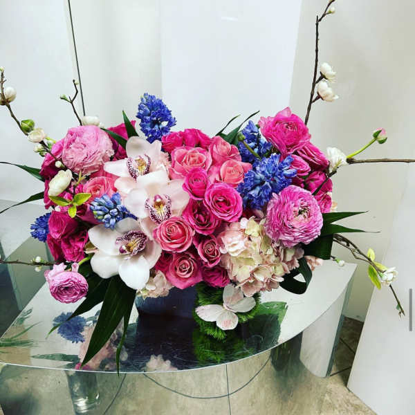 Pink and blue floral arrangement with orchids and roses in a vase
