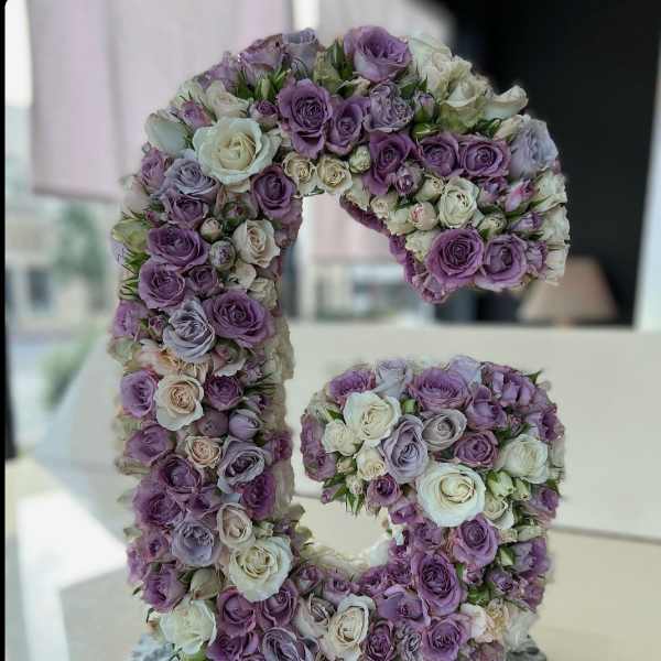 Floral arrangement shaped like the number 5 with purple and white roses