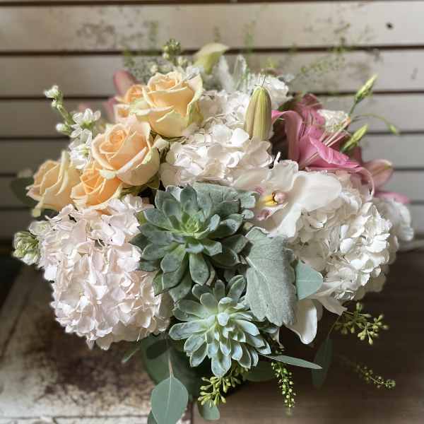 Bouquet of peach roses, white hydrangeas, pink lilies, and succulents
