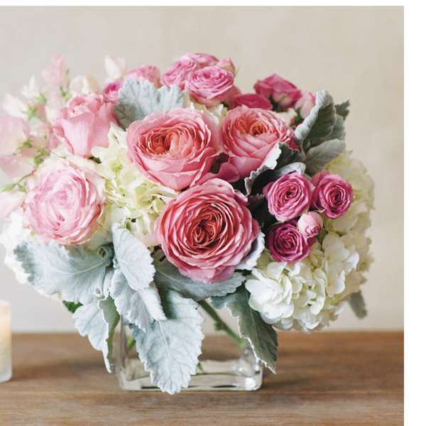 Pink rose bouquet in a clear glass vase with white hydrangeas