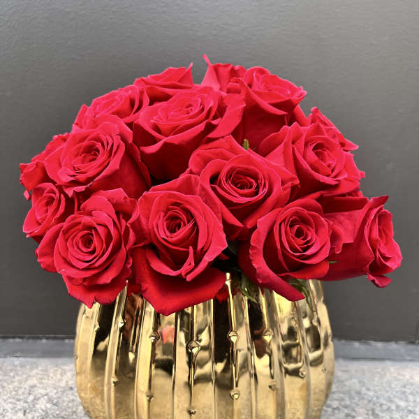 Red roses arranged in a gold ribbed vase