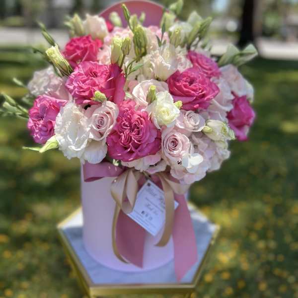 Pink and white rose bouquet in a pink hat box with ribbon