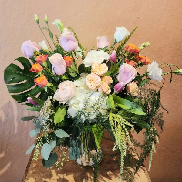 Pastel bouquet of roses and white blooms in a clear glass vase
