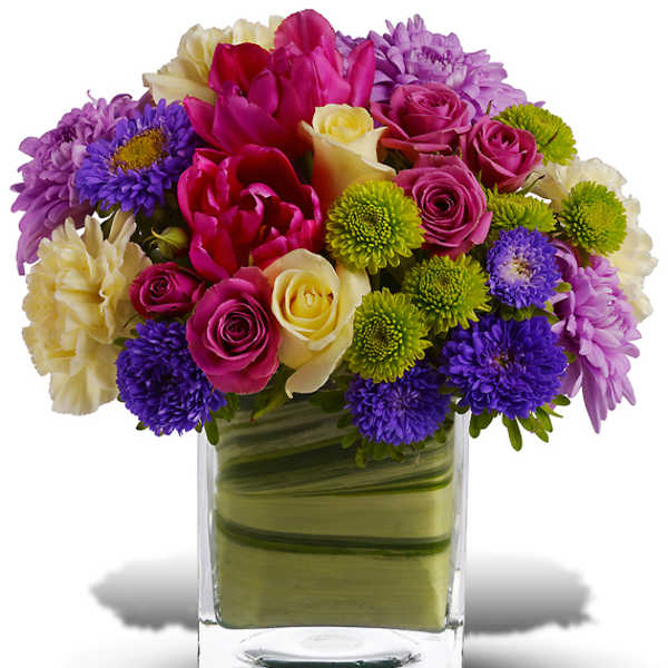 Colorful bouquet of roses, tulips, and mums in a glass vase