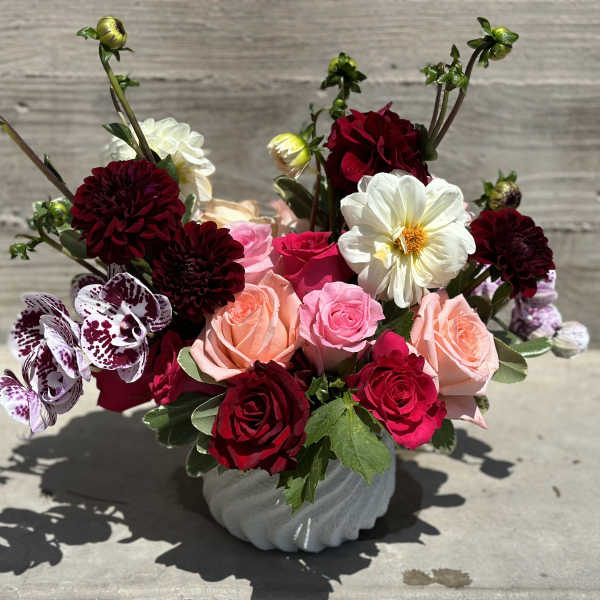 Mixed bouquet of roses and dahlias in a gray vase
