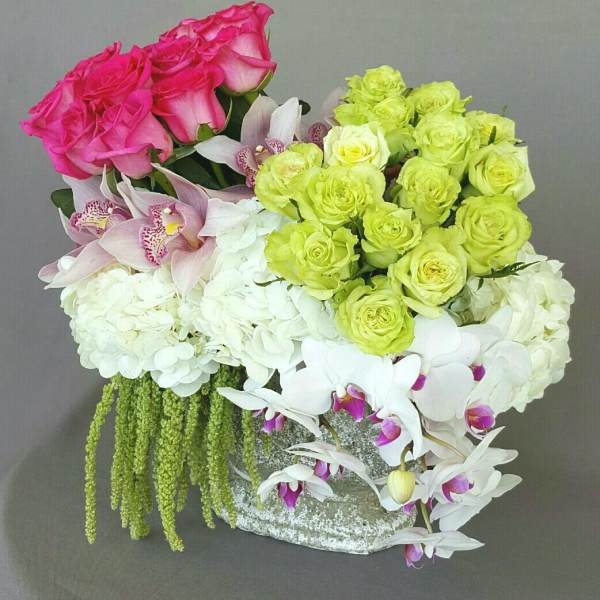 Pink and lime roses with white hydrangeas and orchids in a low container