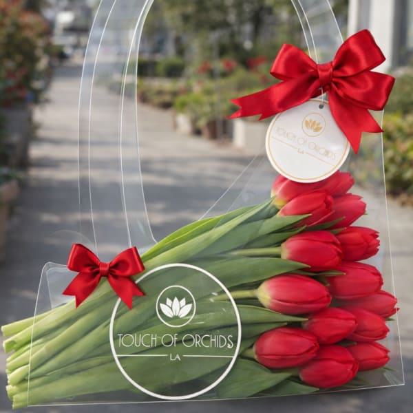 Red tulips in a clear handled gift bag with red bows