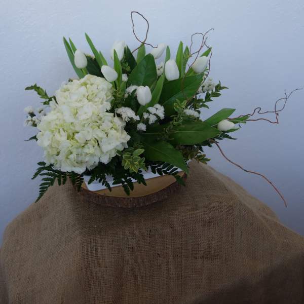 White floral arrangement with tulips and hydrangeas in a low container