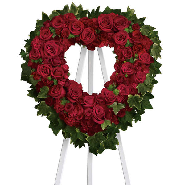 Heart-shaped red rose wreath on a white easel