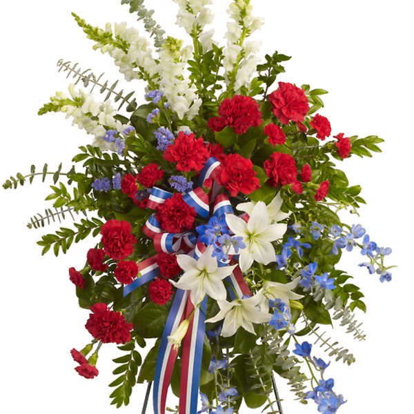 Standing floral spray with red carnations, white lilies, and blue flowers