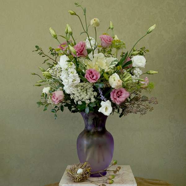 Pink and white mixed bouquet in a purple glass vase