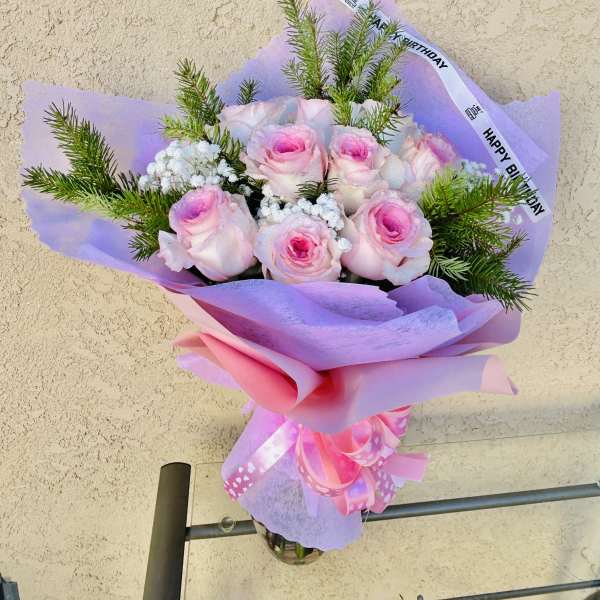 Pink roses in lavender wrap with a birthday ribbon
