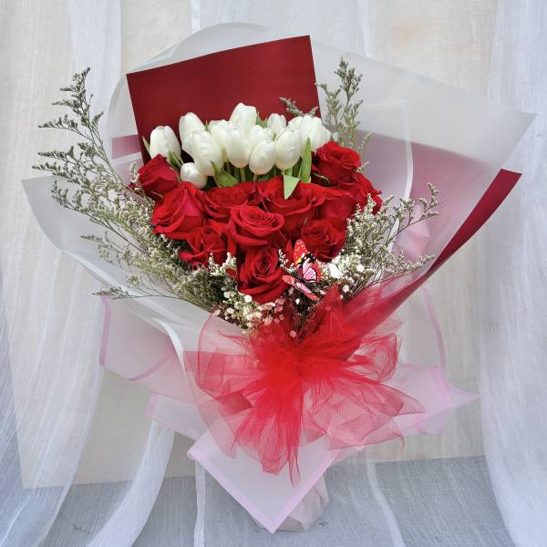 Bouquet of red roses and white tulips wrapped in red and white paper
