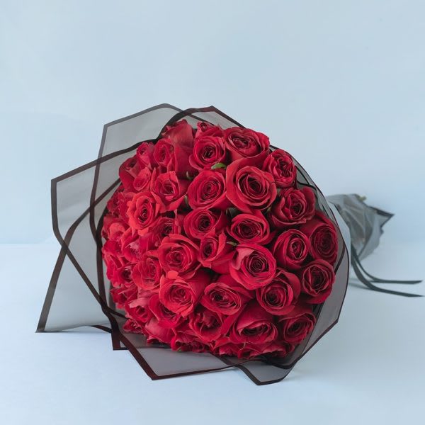 Bouquet of red roses wrapped in dark sheer paper