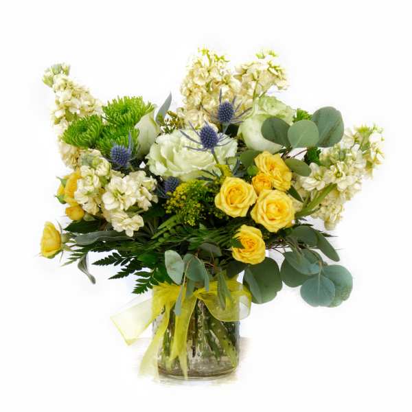 Yellow roses and white flowers in a glass vase with a ribbon