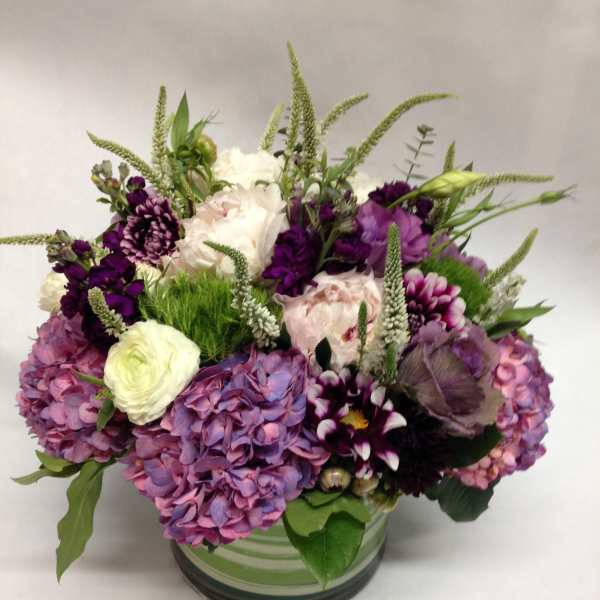 Mixed purple and white flowers arranged in a glass vase