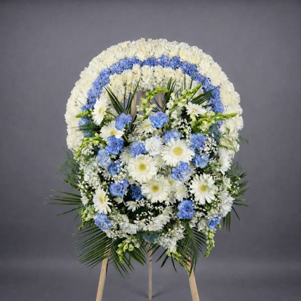 Standing round wreath of white and blue flowers on a wooden easel